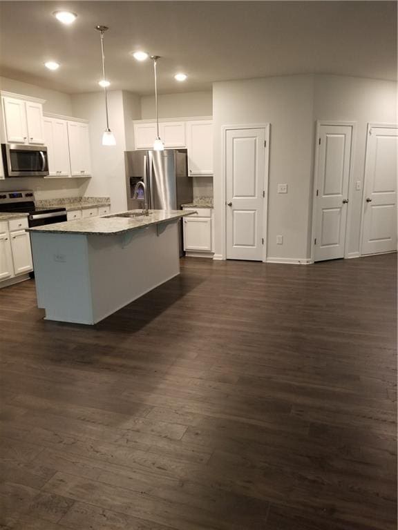 kitchen featuring white cabinets, appliances with stainless steel finishes, a kitchen island with sink, dark hardwood / wood-style floors, and pendant lighting