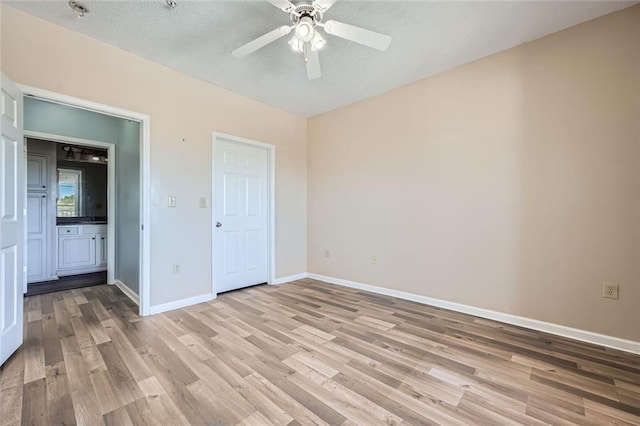 unfurnished bedroom with ceiling fan, connected bathroom, a textured ceiling, and light hardwood / wood-style flooring