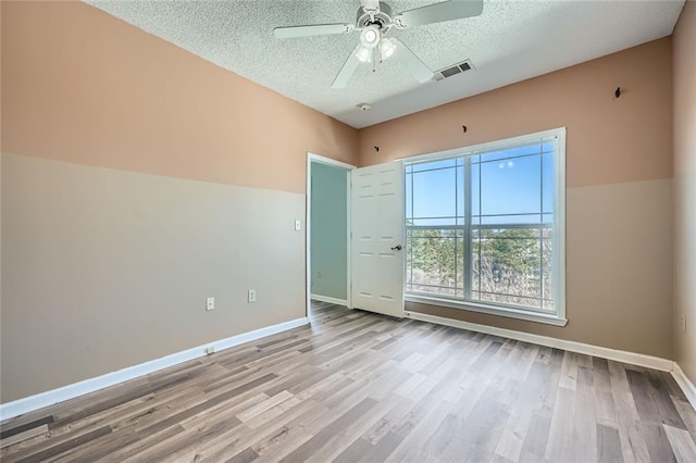 unfurnished room featuring ceiling fan, light hardwood / wood-style floors, and a textured ceiling