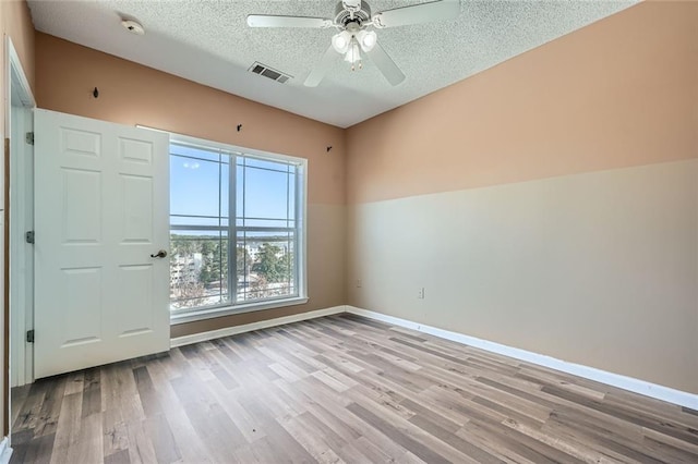 spare room featuring ceiling fan, light hardwood / wood-style floors, and a textured ceiling