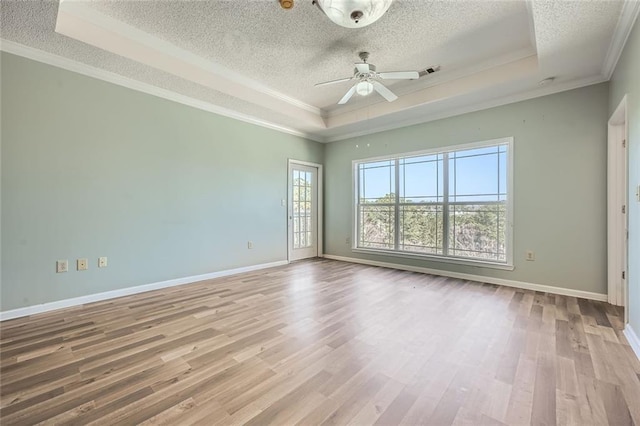 empty room featuring a raised ceiling, crown molding, a textured ceiling, and light hardwood / wood-style flooring