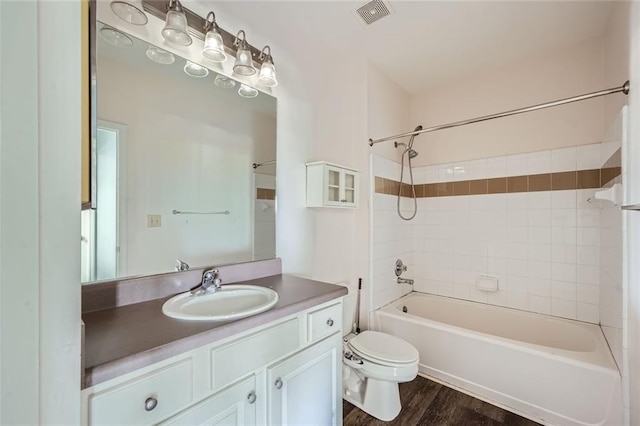 full bathroom featuring vanity, toilet, tiled shower / bath combo, and hardwood / wood-style floors