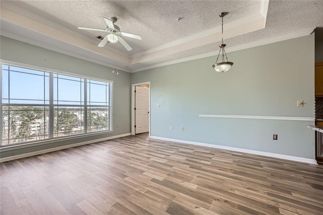 spare room featuring a raised ceiling, hardwood / wood-style flooring, and a textured ceiling