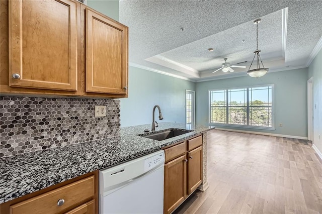 kitchen with decorative light fixtures, dishwasher, sink, ornamental molding, and a raised ceiling