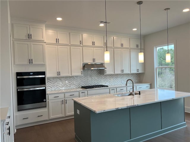 kitchen with hanging light fixtures, white cabinetry, light stone countertops, and sink