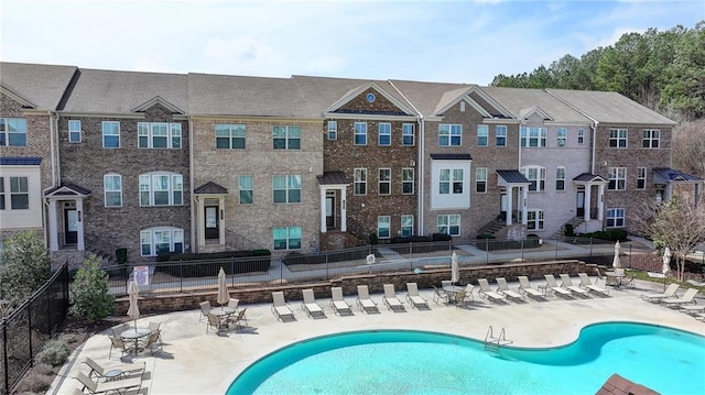 community pool with a patio area and fence