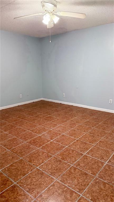 empty room featuring ceiling fan, a textured ceiling, and baseboards