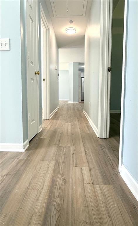 corridor with attic access, wood finished floors, and baseboards
