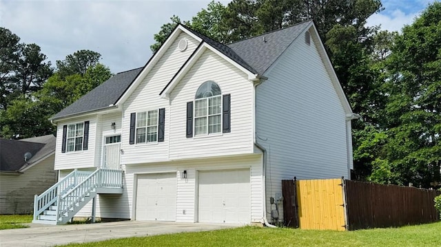 split foyer home featuring a garage, fence, driveway, and a shingled roof