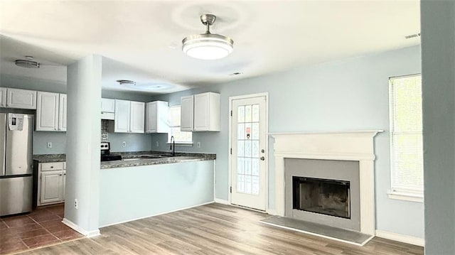 kitchen featuring fridge, electric range, a fireplace, baseboards, and a sink