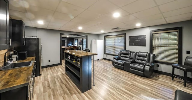 kitchen with wooden counters, sink, a drop ceiling, light wood-type flooring, and white fridge