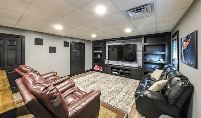 living room with hardwood / wood-style floors, a paneled ceiling, and built in shelves