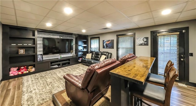 living room with a drop ceiling and light wood-type flooring