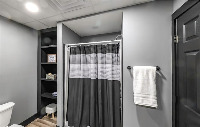 bathroom with toilet, wood-type flooring, a drop ceiling, and curtained shower