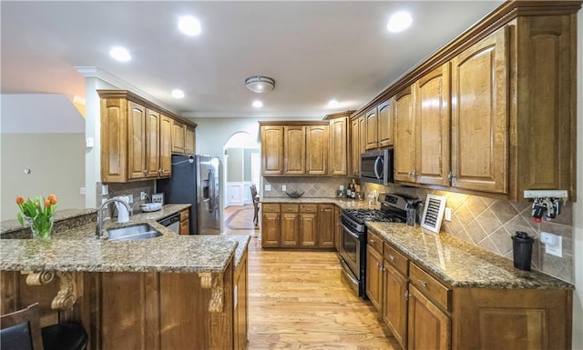 kitchen featuring sink, stone countertops, kitchen peninsula, stainless steel appliances, and light hardwood / wood-style flooring