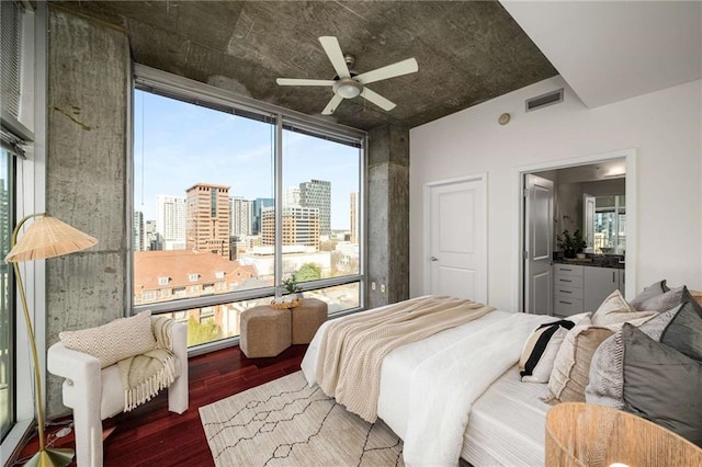 bedroom with visible vents, a city view, expansive windows, wood finished floors, and a ceiling fan