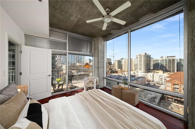 bedroom featuring a view of city, wood finished floors, floor to ceiling windows, and access to exterior