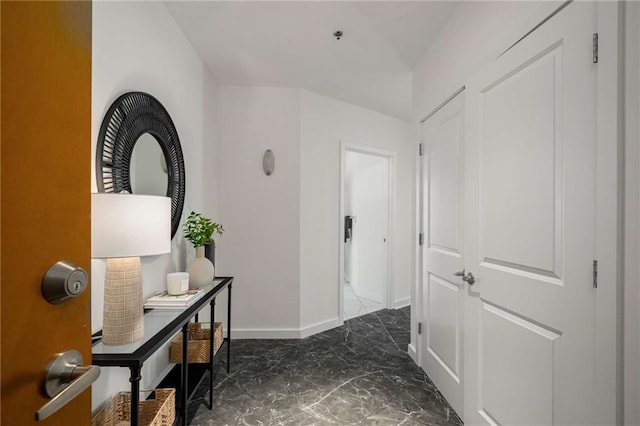 hallway featuring marble finish floor and baseboards