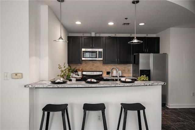 kitchen with a breakfast bar, decorative backsplash, dark cabinetry, marble finish floor, and stainless steel appliances