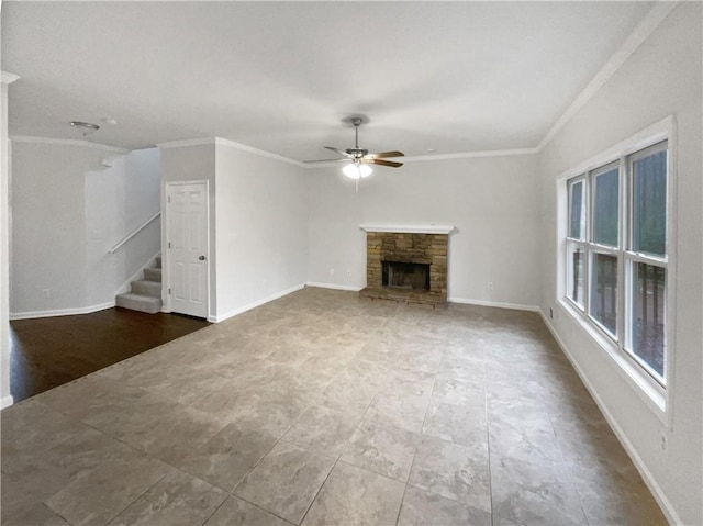 unfurnished living room with baseboards, a ceiling fan, stairs, crown molding, and a stone fireplace