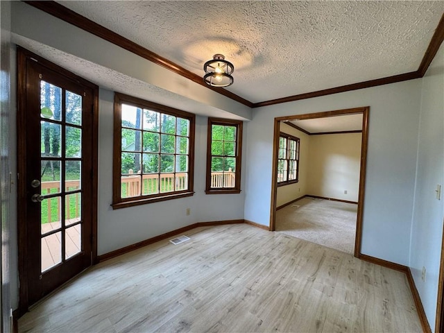 empty room featuring a textured ceiling, light wood-type flooring, ornamental molding, and baseboards