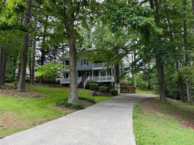view of front of house featuring covered porch, driveway, a front lawn, and stairway