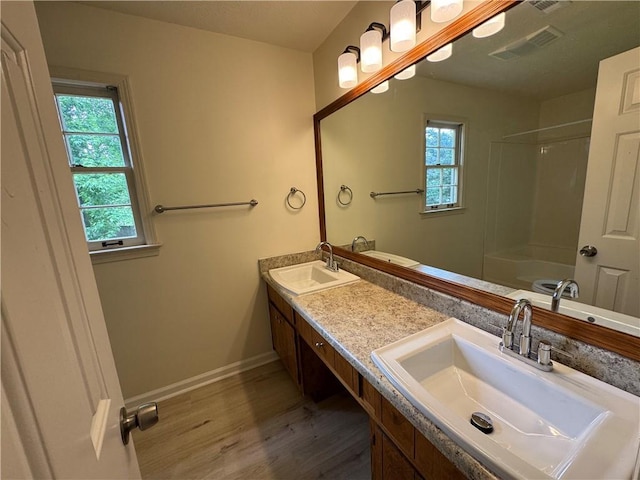 full bath featuring wood finished floors, plenty of natural light, double vanity, and baseboards