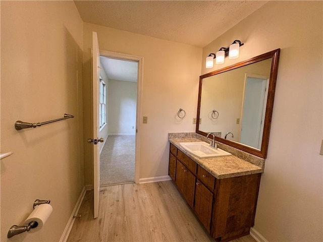 bathroom featuring wood finished floors, vanity, baseboards, and a textured ceiling