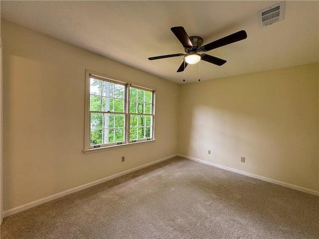 carpeted spare room featuring baseboards and a ceiling fan