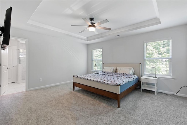 carpeted bedroom featuring multiple windows, a raised ceiling, and ceiling fan