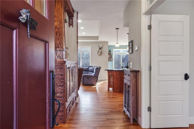 hallway featuring baseboards, wood finished floors, and recessed lighting