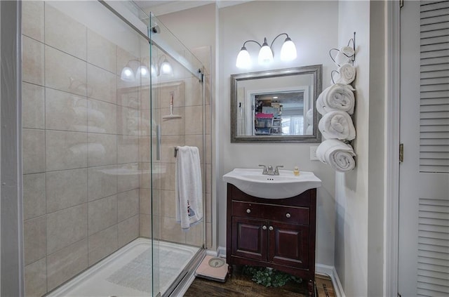 bathroom with a stall shower, vanity, baseboards, and wood finished floors