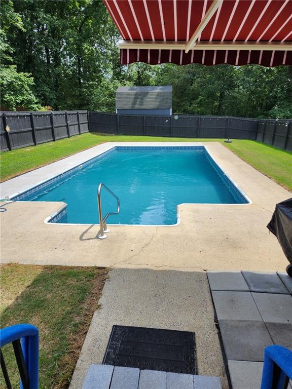 view of swimming pool with a patio area, a fenced backyard, a fenced in pool, and a lawn