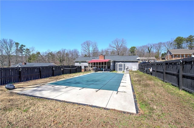 view of pool with fence, a yard, an outdoor structure, a fenced in pool, and a patio area