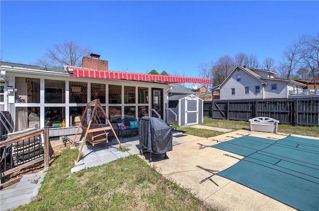 rear view of house featuring fence, a chimney, a patio area, a storage unit, and an outbuilding