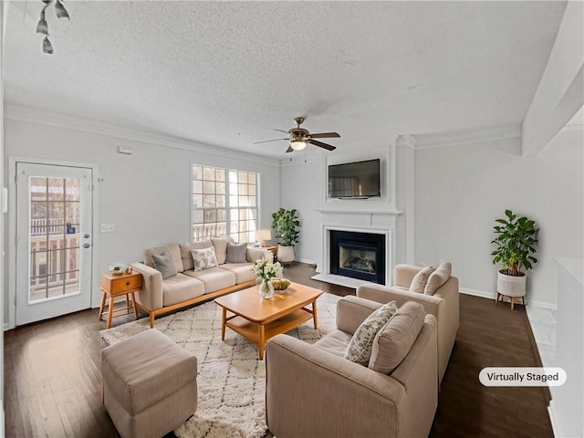 living room featuring a fireplace with flush hearth, a textured ceiling, crown molding, and wood finished floors