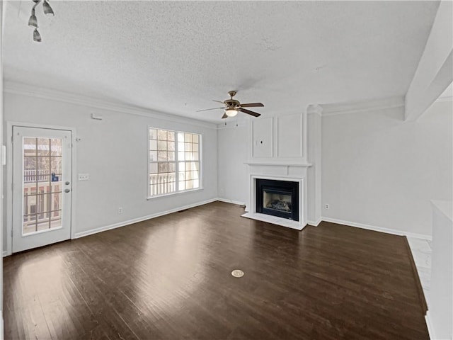 unfurnished living room featuring dark wood-style floors, a fireplace, a textured ceiling, and crown molding