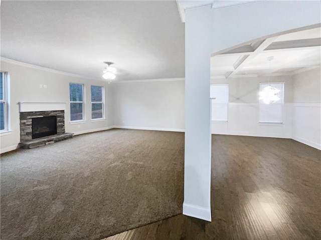 unfurnished living room with beamed ceiling, crown molding, a stone fireplace, and coffered ceiling