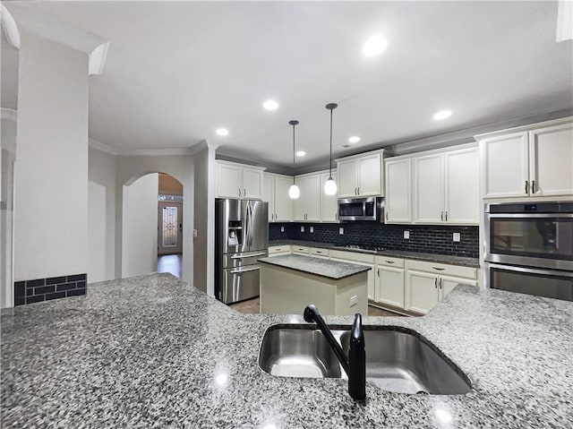 kitchen featuring appliances with stainless steel finishes, sink, dark stone countertops, and backsplash