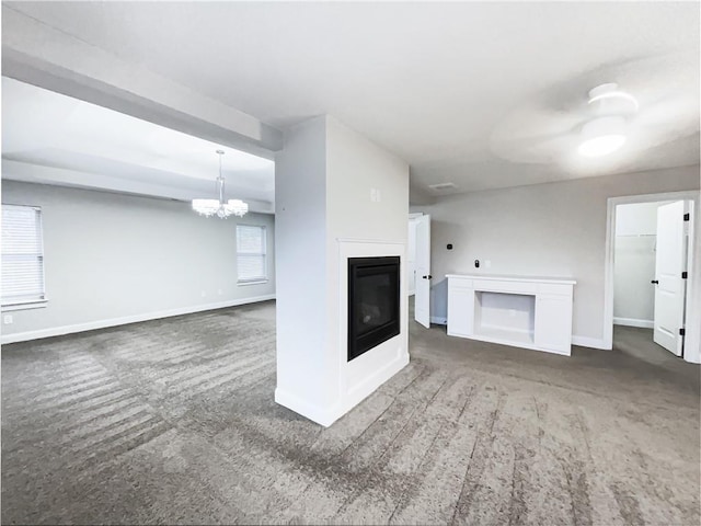 unfurnished living room with a notable chandelier and dark colored carpet