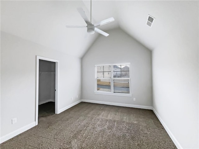 unfurnished bedroom with vaulted ceiling, a walk in closet, carpet flooring, and ceiling fan