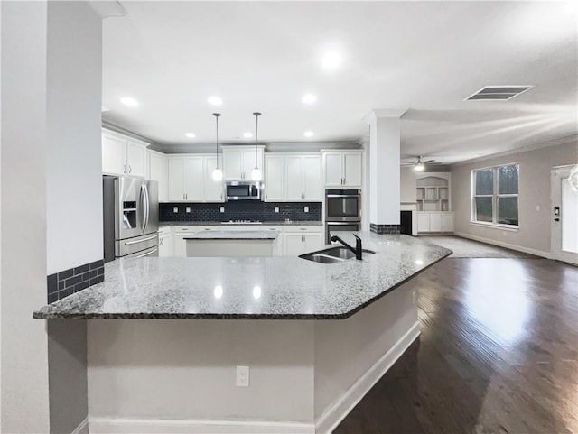 kitchen with appliances with stainless steel finishes, pendant lighting, white cabinets, and dark stone counters