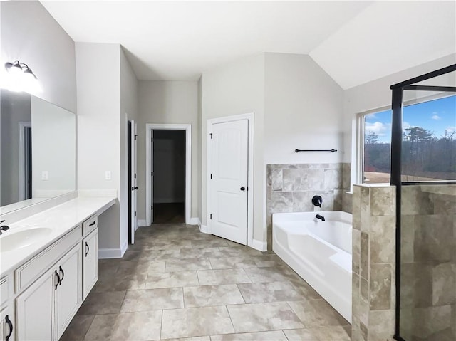 bathroom with vaulted ceiling, tile walls, vanity, a bathing tub, and tile patterned flooring