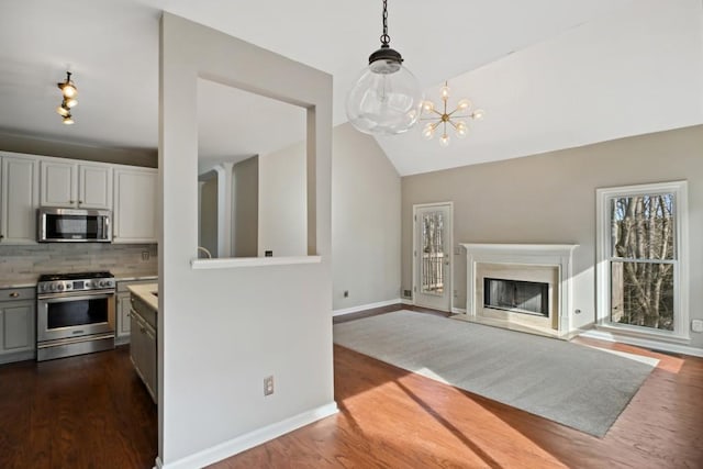 living room featuring vaulted ceiling, dark wood-type flooring, and a notable chandelier