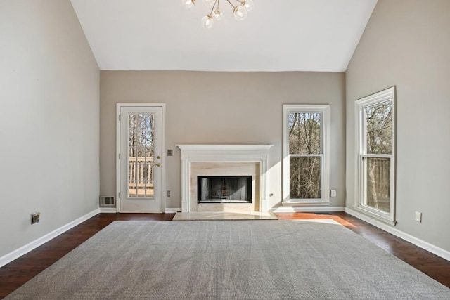 unfurnished living room with dark hardwood / wood-style floors, a high end fireplace, lofted ceiling, and a notable chandelier