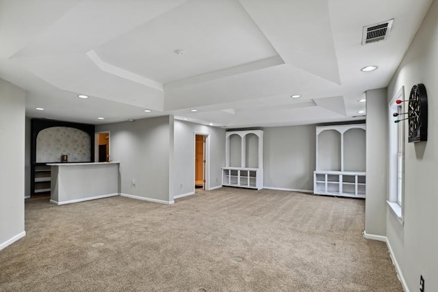 unfurnished living room featuring carpet flooring and a tray ceiling