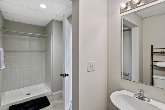 bathroom featuring a shower, sink, toilet, and a paneled ceiling