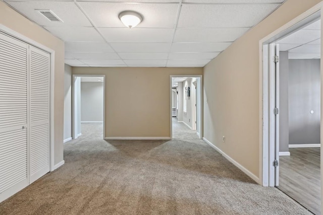 corridor featuring a paneled ceiling and light carpet