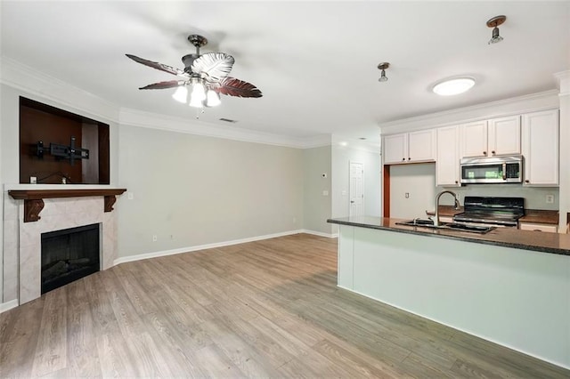 kitchen featuring ceiling fan, a sink, stainless steel microwave, dark countertops, and electric range