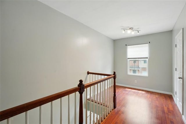 hallway featuring baseboards, an upstairs landing, and wood finished floors